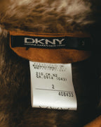 首元内側に配されたDKNY DONNA KARAN NEW YORKの織りタグと、ダナキャランジャパン株式会社の表記が読める国内品質表示タグのカット。シアリングの毛足とキャメルブラウンのスエード面も確認できます。