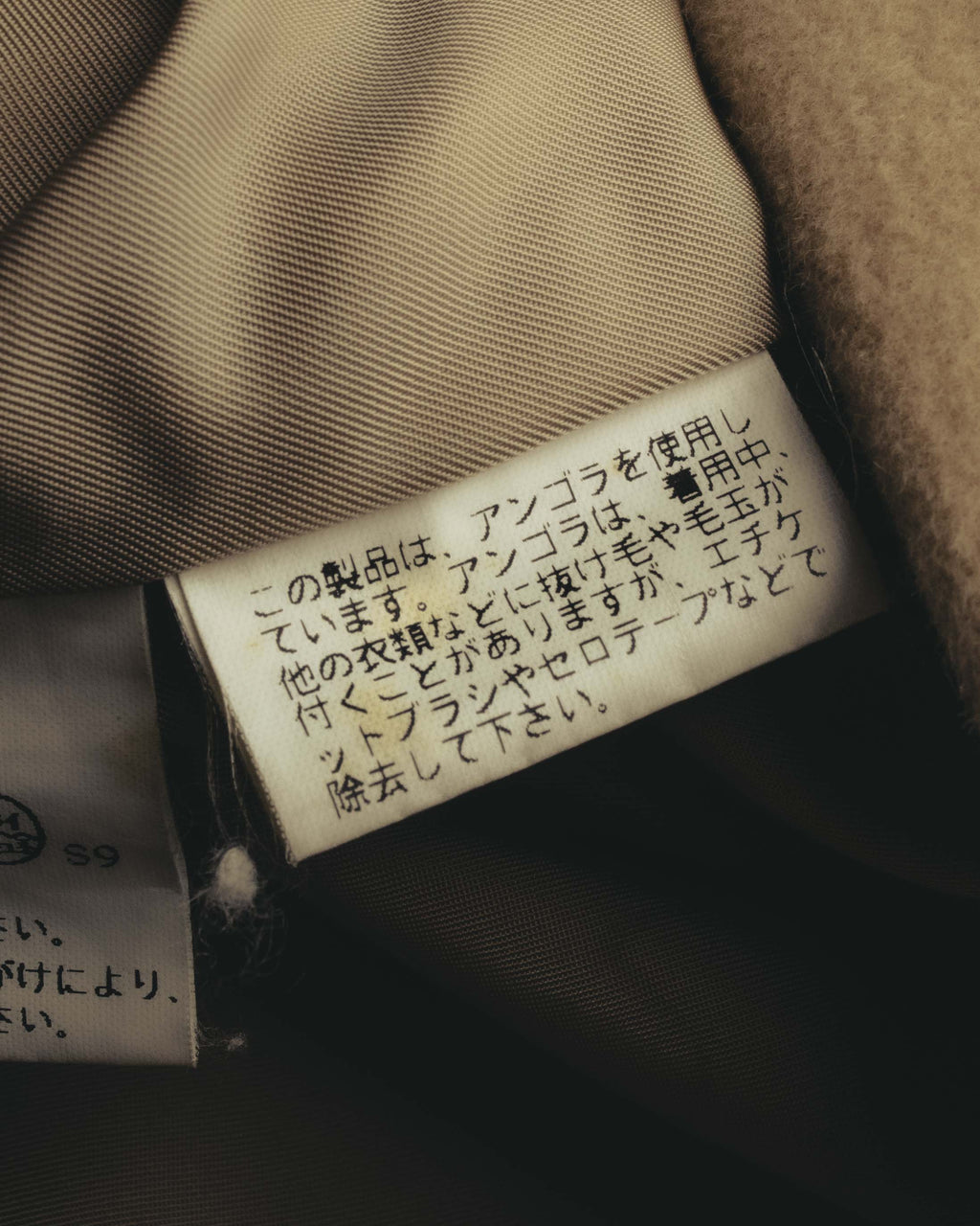アンゴラ使用に関する注意書きが読める、日本語の品質表示タグのクローズアップ。滑らかなキュプラ裏地とあわせて確認できるカットです。