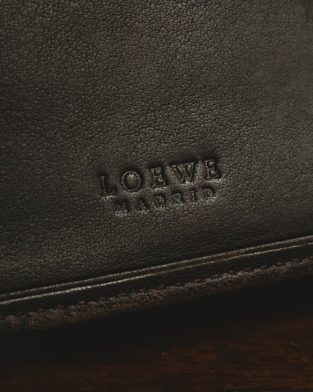 きめ細かなシボを感じさせる内装レザーに配された、セリフ体のLOEWE MADRID刻印を捉えたディテールカット。下部には札入れ口の縁と縫製が写ります。