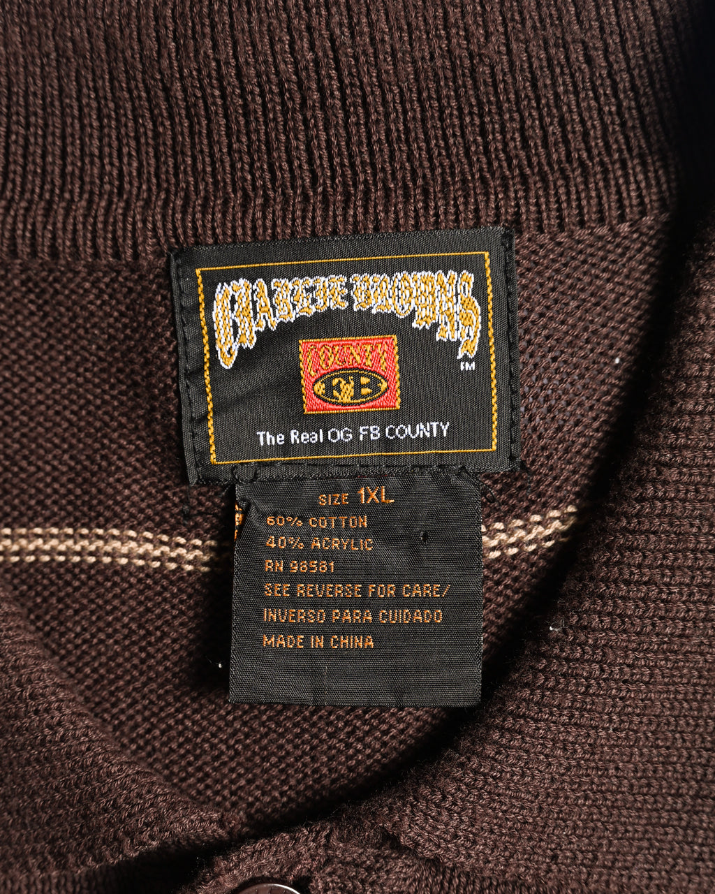 首元に配されたFB COUNTYのネックラベルと品質表示タグのカット。表記サイズ1XL、綿60％・アクリル40％の混紡ニットを確認できます。