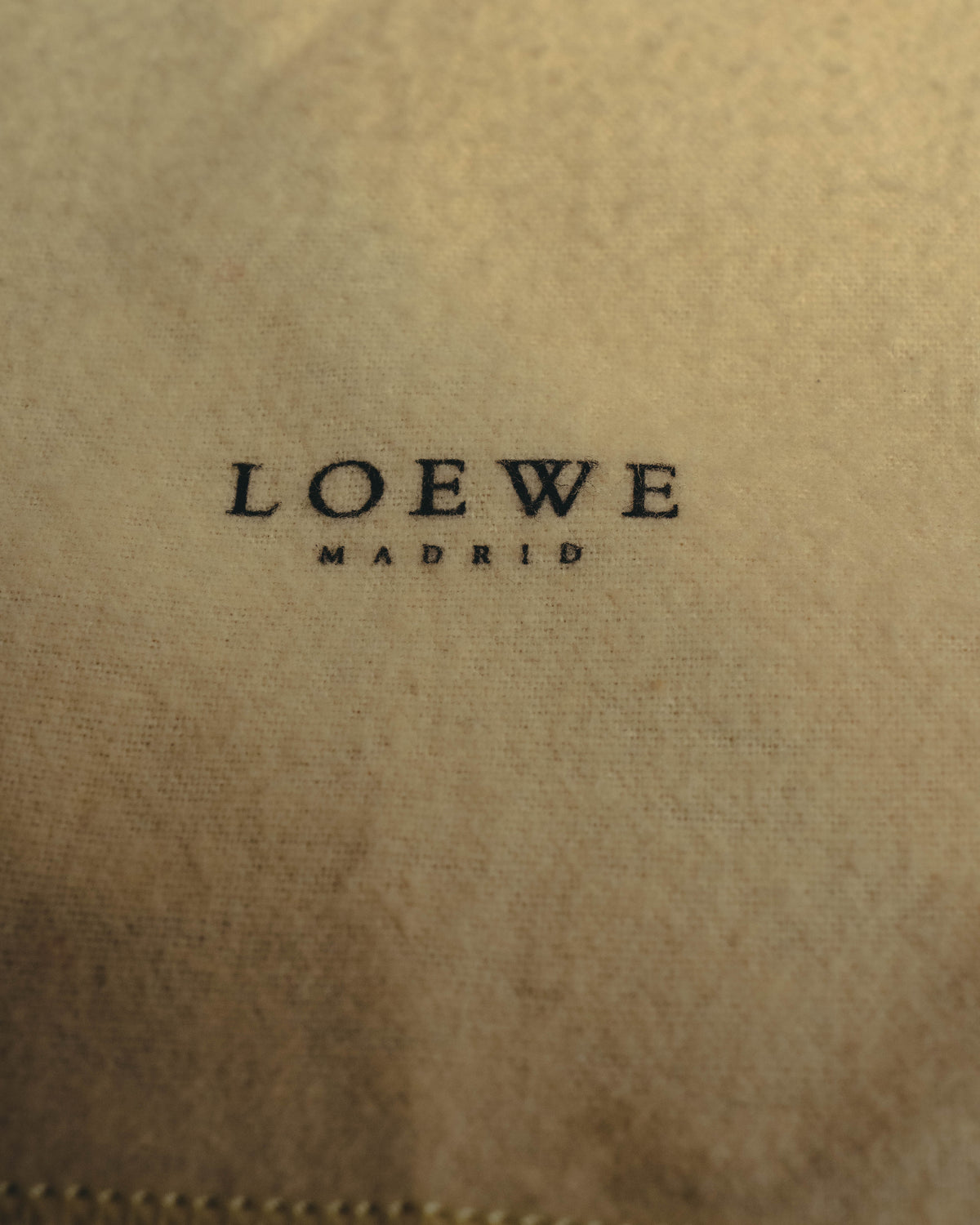 生成りに近い付属布に入る、LOEWE MADRIDのプリントを捉えたディテールカット。布地表面の細かな織りと、下端の縫製も確認できます。