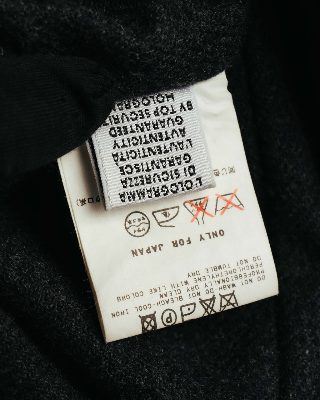 内側に配された品質表示タグと洗濯表示のクローズアップ。ウール・ポリアミドの表地表記、および裏地・内側素材に関する表記を確認できるカットです。