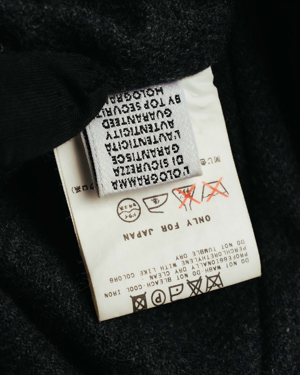 内側に配された品質表示タグと洗濯表示のクローズアップ。ウール・ポリアミドの表地表記、および裏地・内側素材に関する表記を確認できるカットです。