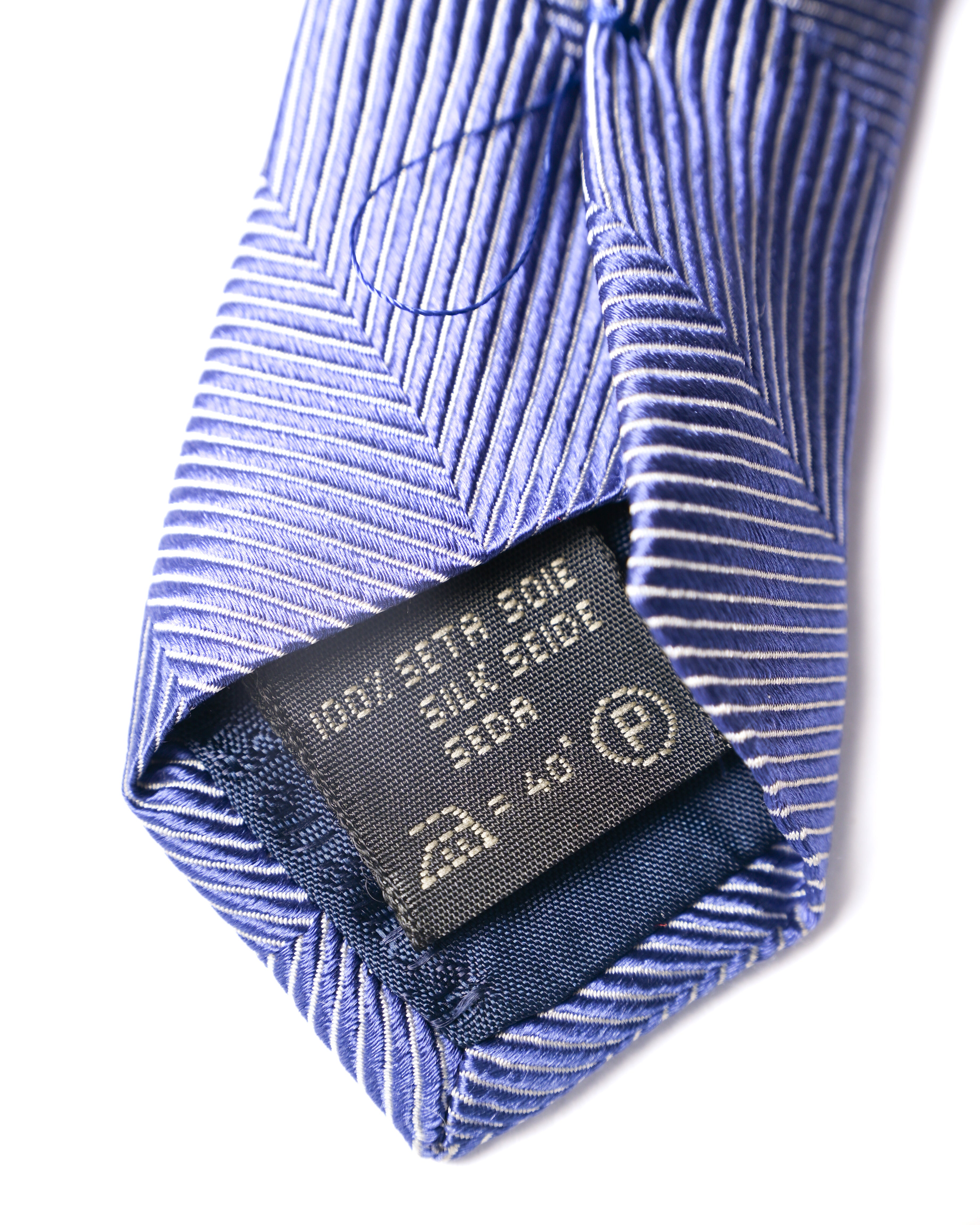 小剣の裏側に配された素材タグのクローズアップ。SILK 100%表記と、周囲の裏地・ループ処理を確認できるカットです。