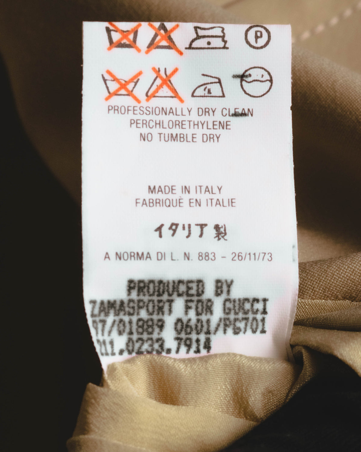 MADE IN ITALY表記と、GUCCI向けの製造元・管理コードが確認できる洗濯表示タグのカット。ドライクリーニング指定およびタンブル乾燥不可のケア表示を掲載。