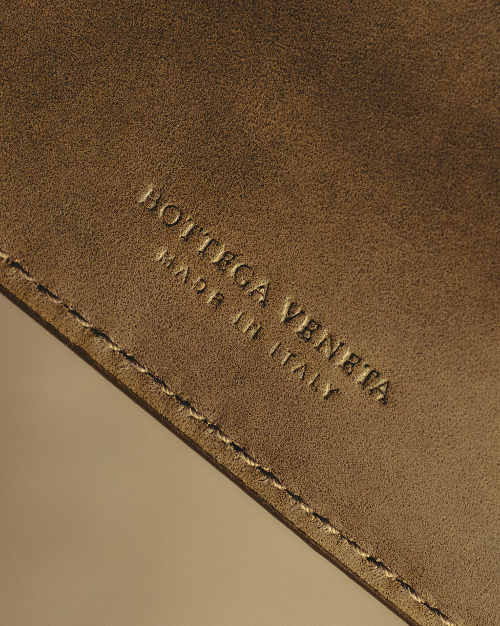 内装レザーに控えめに配された、BOTTEGA VENETA と MADE IN ITALY の型押しを捉えたディテールカット。細身で字間を広く取った旧調のロゴと、縁のステッチを確認できます。