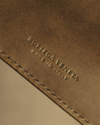内装レザーに控えめに配された、BOTTEGA VENETA と MADE IN ITALY の型押しを捉えたディテールカット。細身で字間を広く取った旧調のロゴと、縁のステッチを確認できます。
