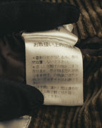 内側に配された旧JIS形式のケア表示タグを写したカット。日本語の取扱い表示とともに、総裏の滑らかな裏地と太畝コーデュロイの裏側が確認できます。