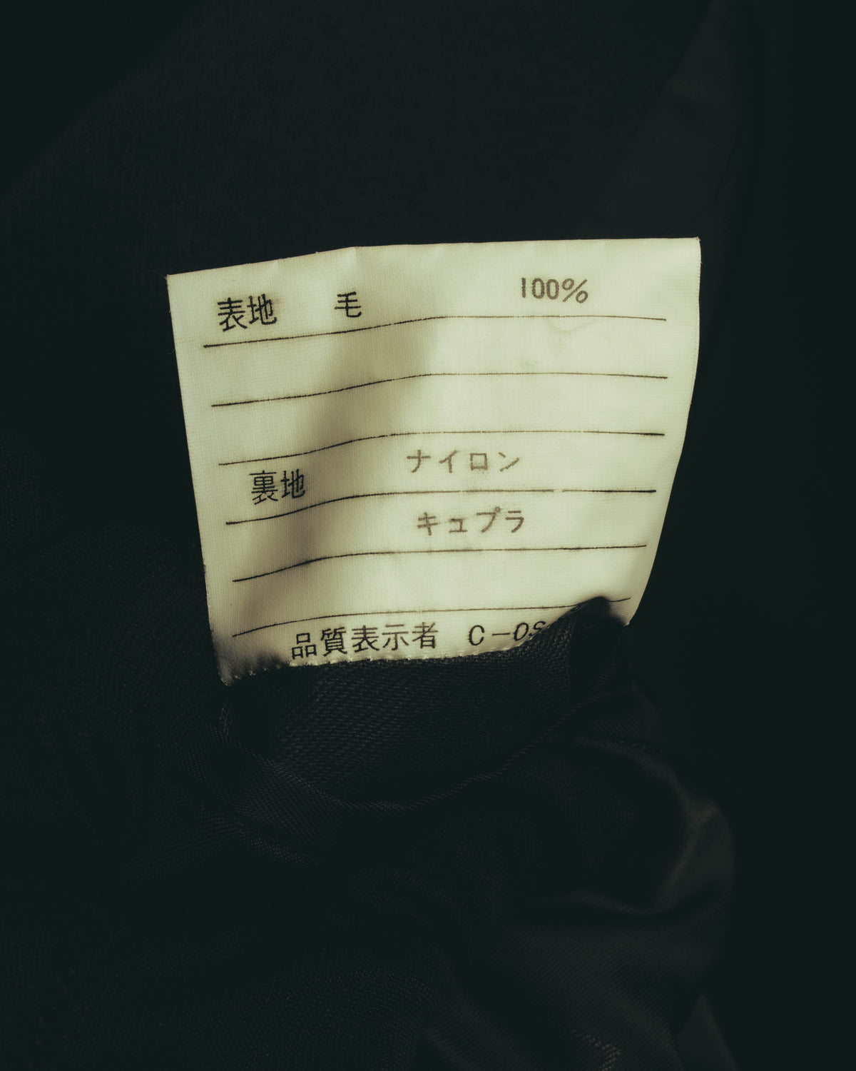 内側の品質表示タグを写したカット。表地は毛100%、裏地にはナイロンとキュプラの表記が確認できます。