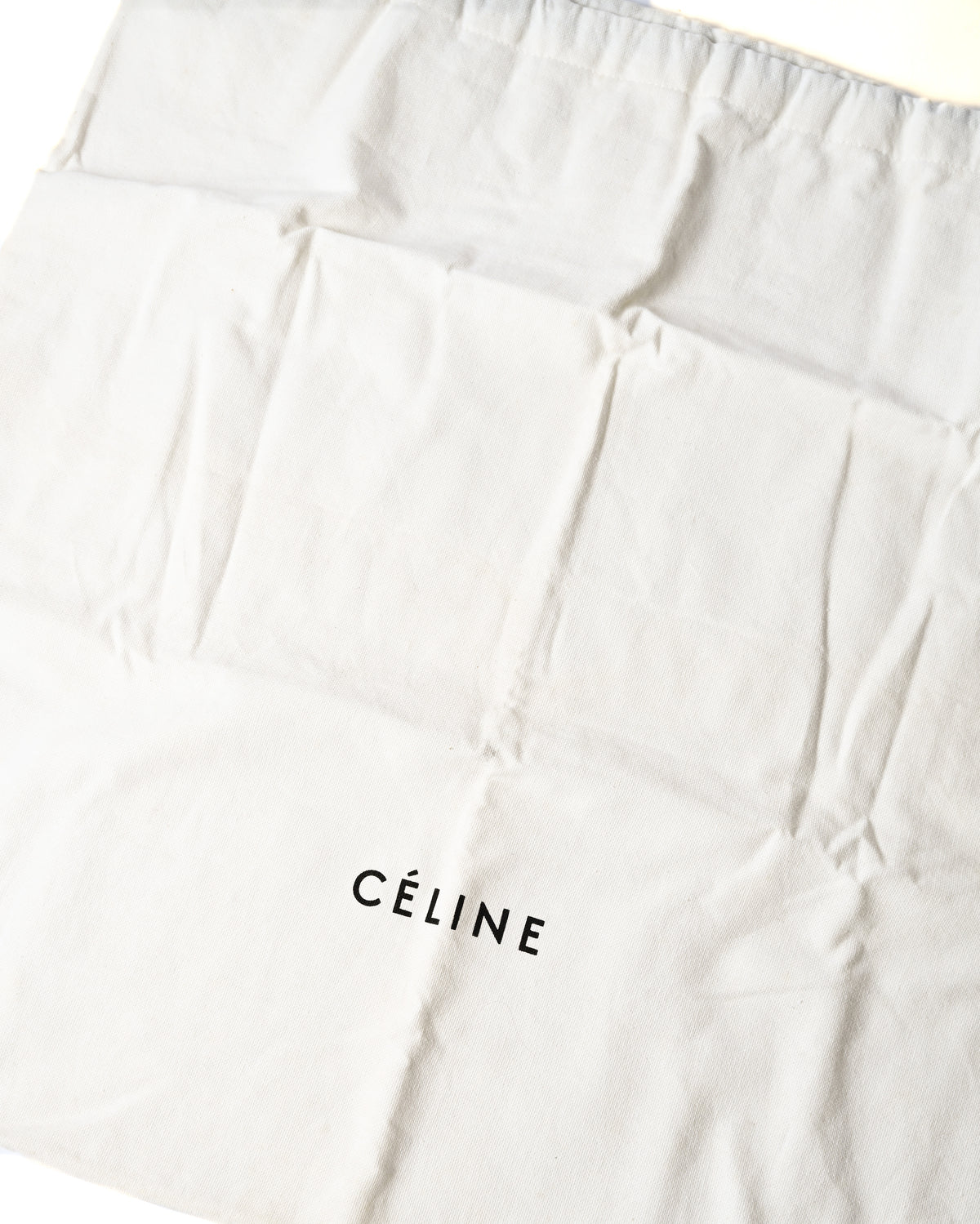 「CÉLINE」ロゴがプリントされた白い保存袋のカット。バッグ本体に付属する保管用の布袋を確認できます。