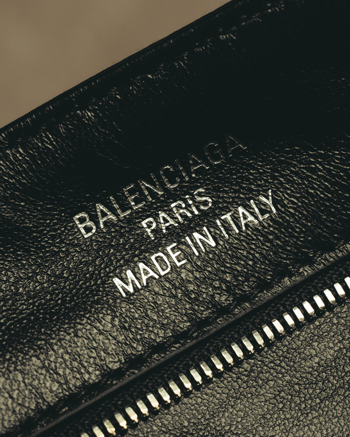 シボ感のあるブラックの内装に施された「BALENCIAGA PARIS MADE IN ITALY」の銀色箔押しと、ファスナーポケットを捉えたディテールカット。
