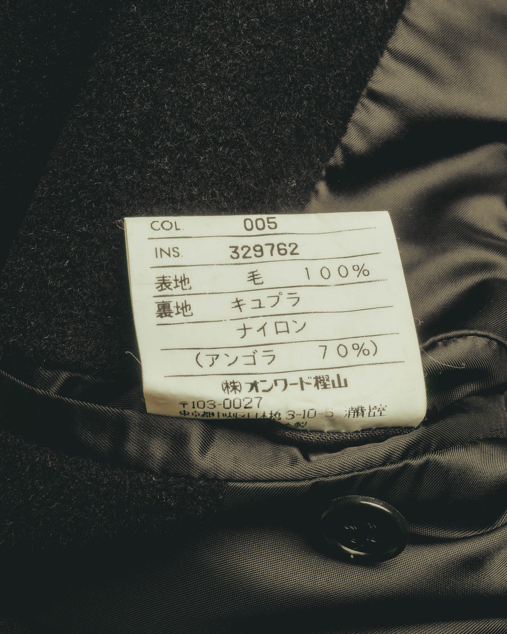 内側の品質表示タグを写したカット。表地は毛100%、裏地はキュプラ・ナイロン（アンゴラ70%）と記載され、INS 329762の国内管理番号も確認できます。