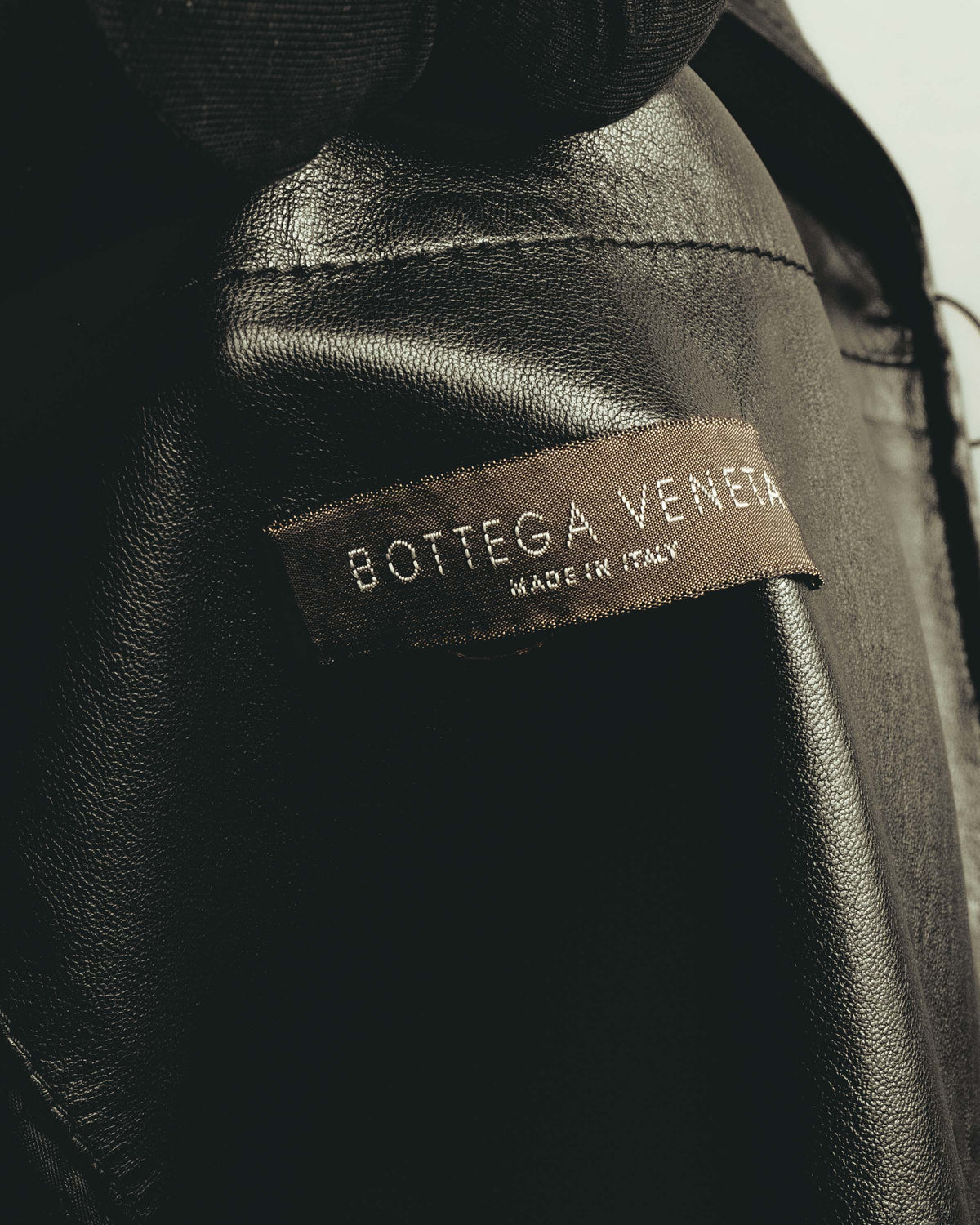 内側に配された「BOTTEGA VENETA」「MADE IN ITALY」表記の織りネームを捉えたカット。ブラックレザーと滑らかな裏地の境目も確認できます。
