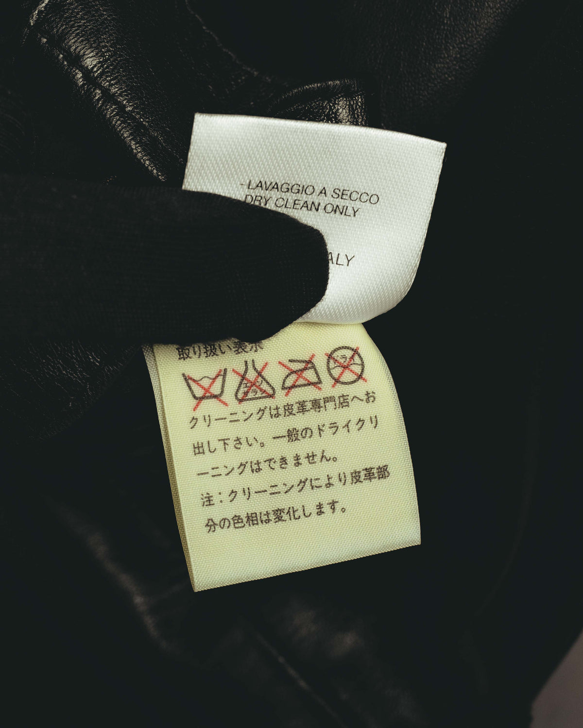 内側に配された洗濯表示タグのクローズアップ。ドライクリーニング表記とイタリア製表記の一部が確認できます。