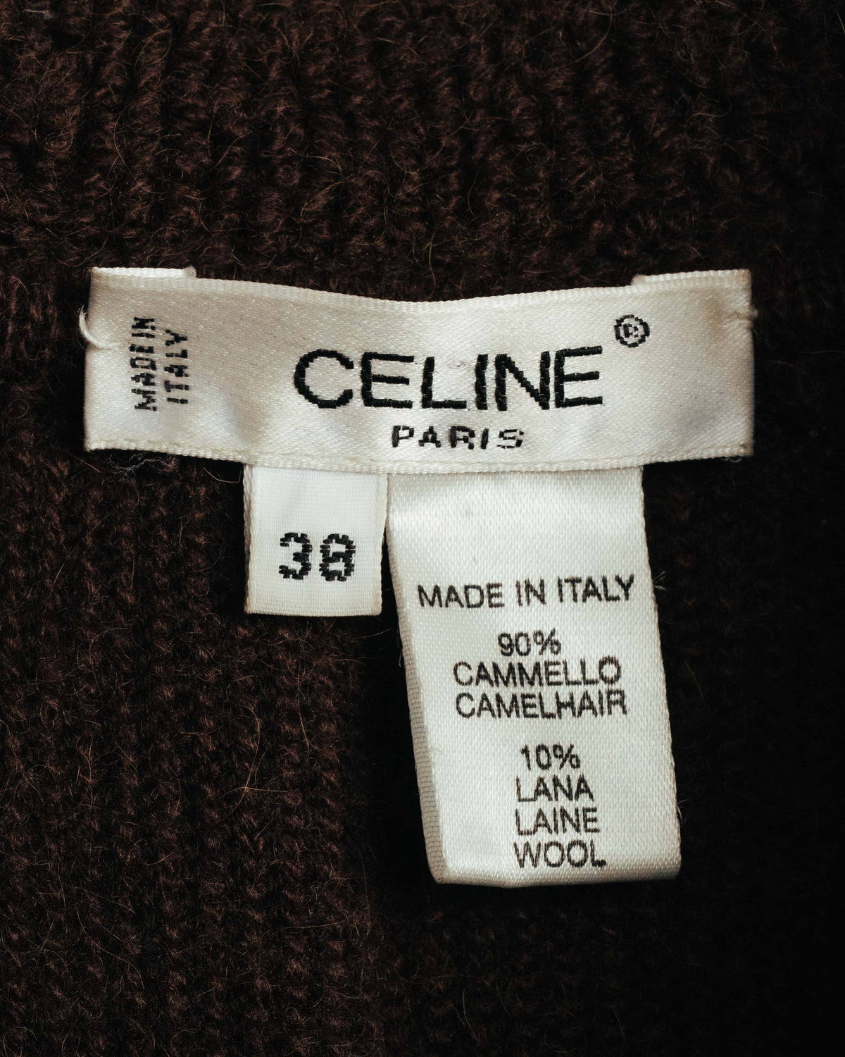 CELINE PARIS表記とMADE IN ITALY表記を確認できる白色のサテン系ネームタグ。表記サイズ38、素材はキャメルヘア90％・ウール10％と記載されています。