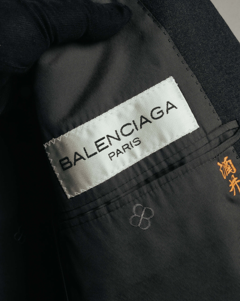内側に配された白地に黒字のBALENCIAGA PARISタグと、内ポケット付近に残る橙色のネーム刺繍を捉えたカット。ダークトーンの裏地にはBBモノグラムも確認できます。