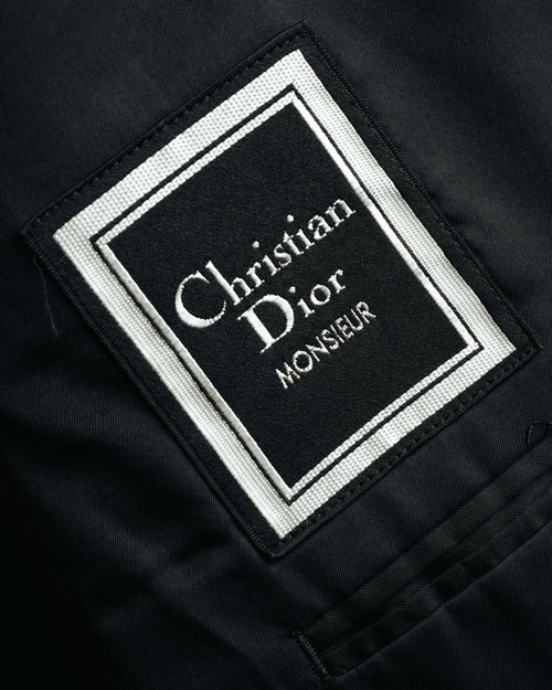 黒地に白い織り文字と二重枠を配した、Christian Dior Monsieurのブランドタグ。滑らかな裏地に縫い付けられた内側のタグを確認できるカット。