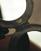 開いた二面ミラーの内側に配された、ゴールドカラーのCartier ParisロゴとMade in Franceの型押しを捉えたカット。ブラックレザーの縁取りと円周に沿うステッチも確認できます。