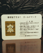 牛革、原産国日本、登録番号7015、日本ハンドバッグ協会の記載が確認できる付属カード。背景には立体的な型押しを施したブラックレザーが写ります。