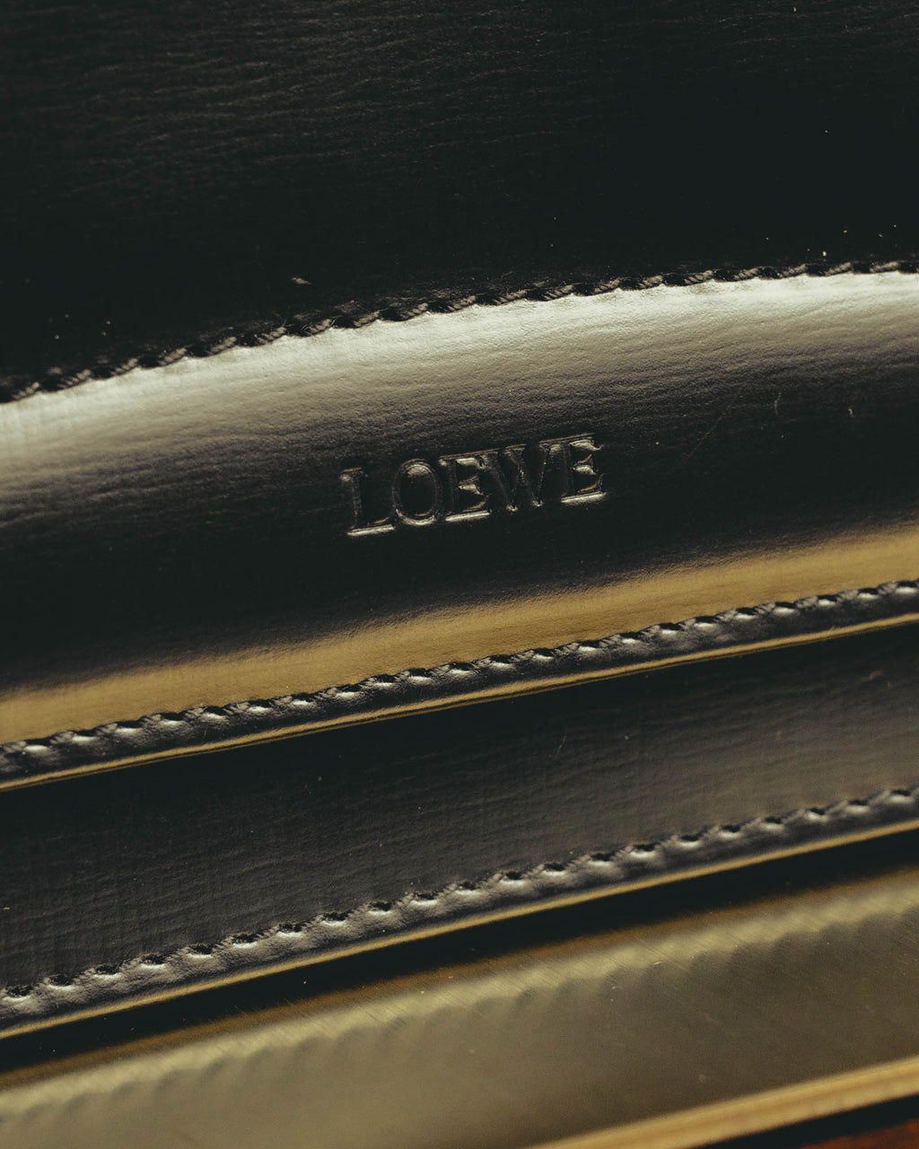 艶を帯びたブラックのフロントに刻まれた「LOEWE」ロゴと、輪郭に沿って施されたステッチを捉えたディテールカット。