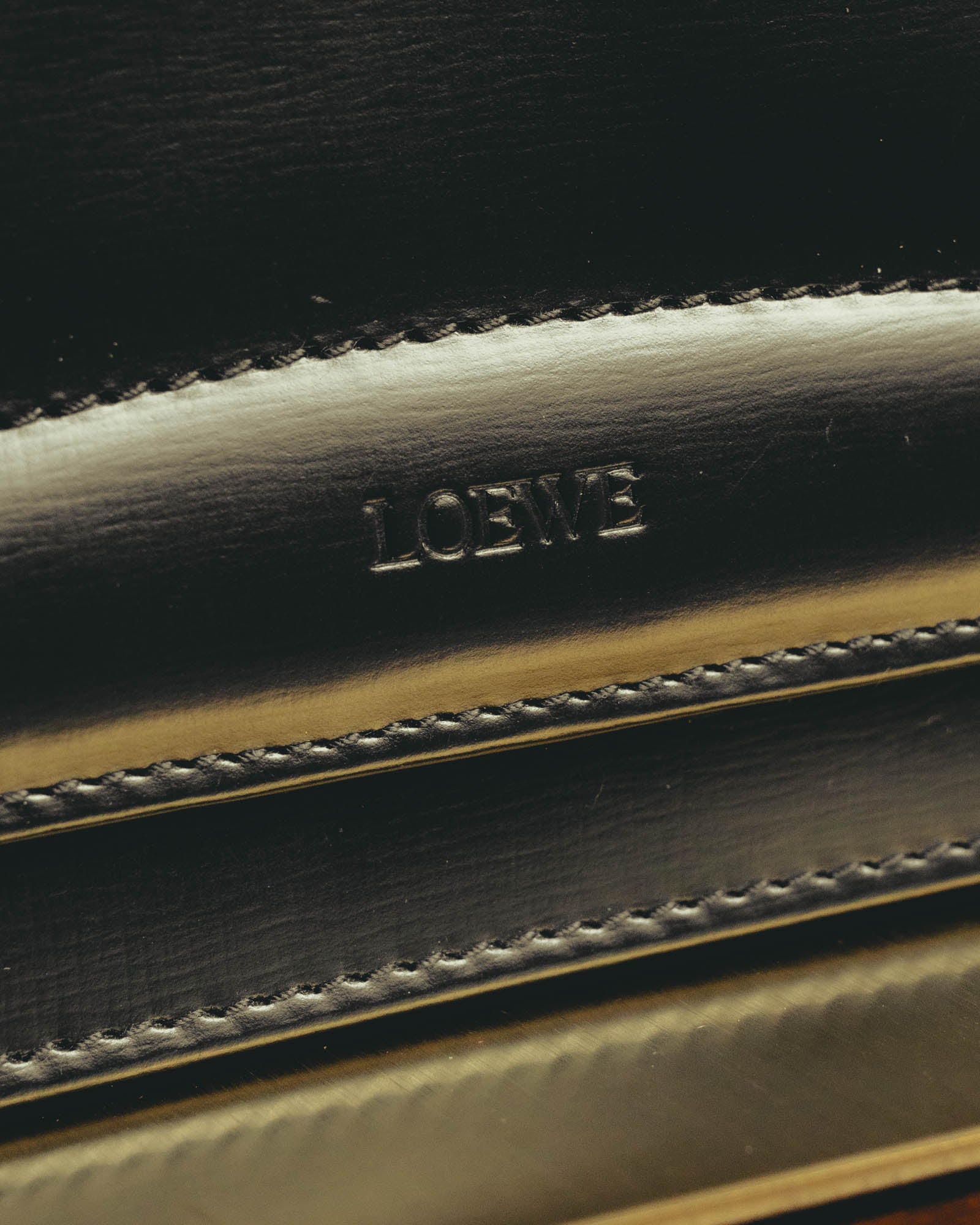 艶を帯びたブラックのフロントに刻まれた「LOEWE」ロゴと、輪郭に沿って施されたステッチを捉えたディテールカット。