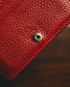 横長二つ折り構造の留め具となる、GUCCI刻印入りスナップボタンのディテールカット。細かなシボを持つレッドレザーと同系色のステッチ、ブラックのコバを確認できます。