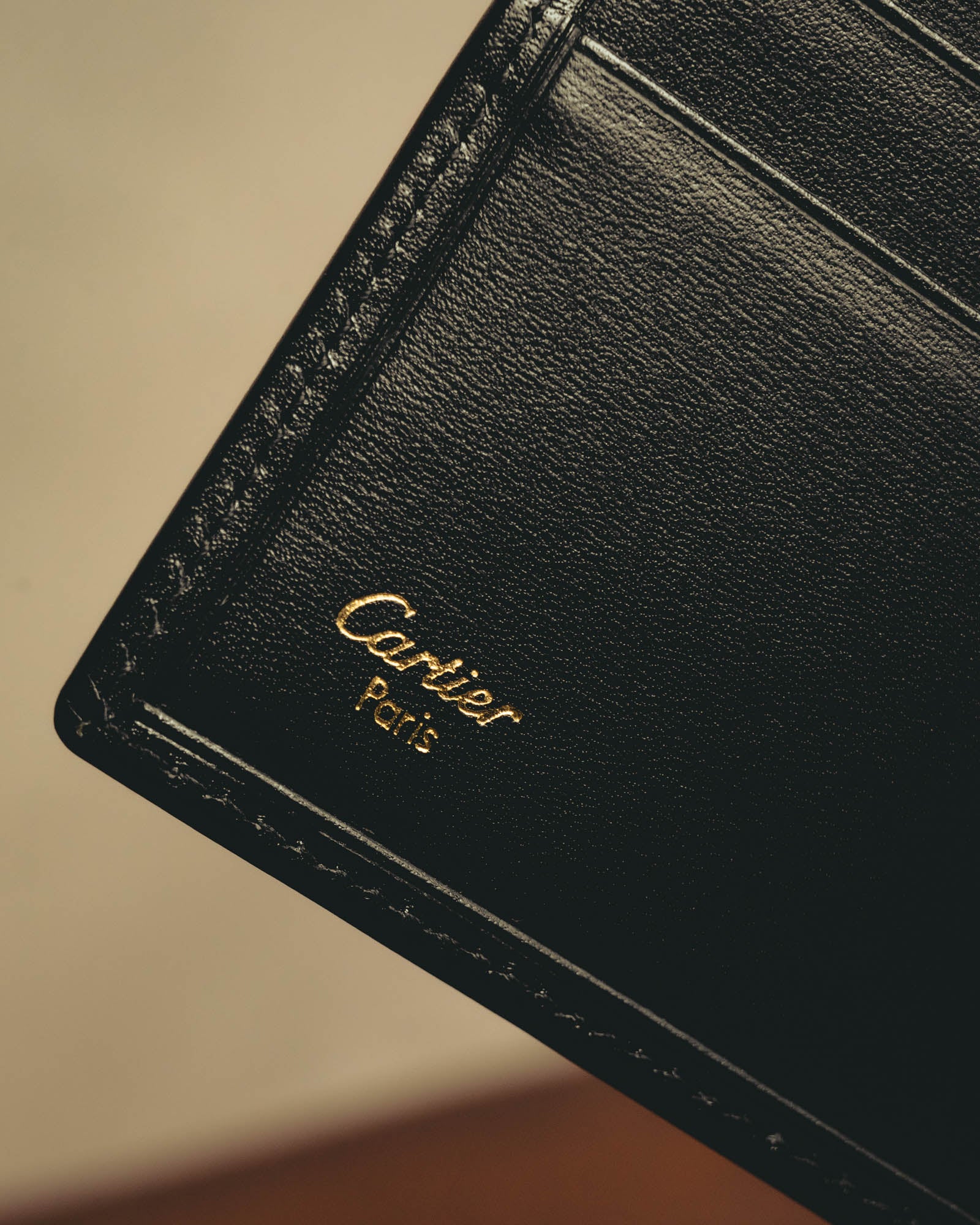 内装に施されたCartier Parisのゴールド箔押しと、カードスロット周辺を捉えたディテールカット。ブラックの細かなシボと同色ステッチも確認できます。