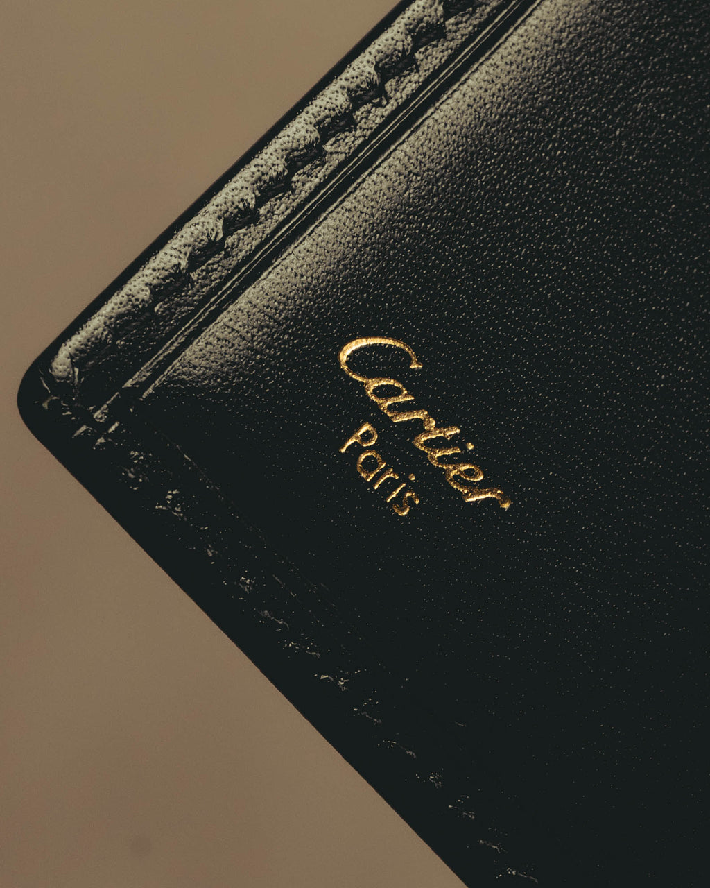 ブラックの内装に施されたCartier Parisのゴールド箔押しと、縁に並ぶカードスロットを捉えたディテールカット。
