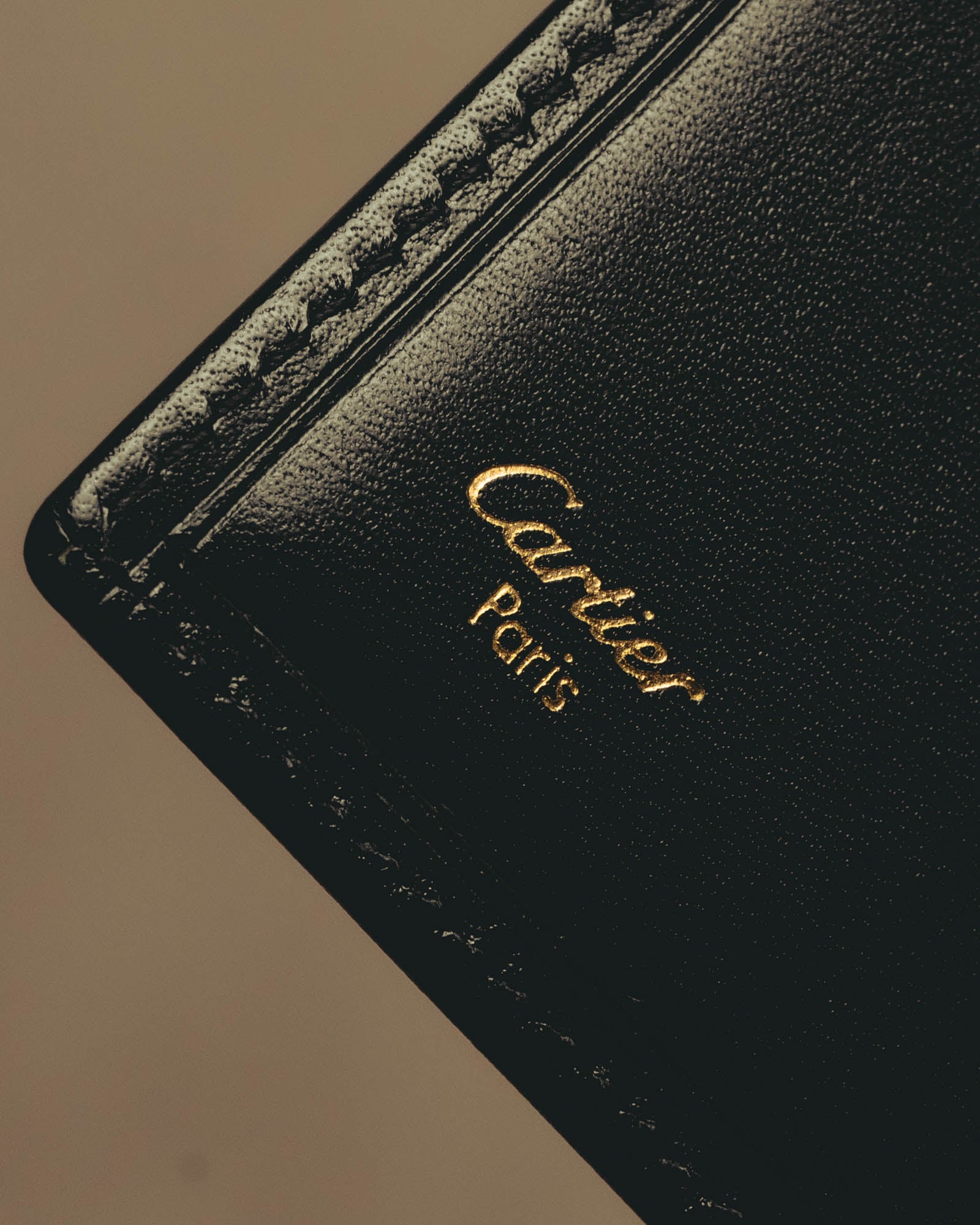 ブラックの内装に施されたCartier Parisのゴールド箔押しと、縁に並ぶカードスロットを捉えたディテールカット。