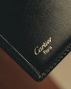 内装に施されたCartier Parisのゴールド箔押しと、縁に沿った同色ステッチを捉えたディテールカット。カードスロットの一部と細かなシボを備えた革様素材の表情が確認できます。