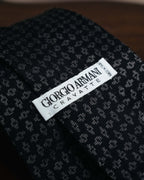 GIORGIO ARMANI、CRAVATTE、MADE IN ITALYの表記が入る白地の織りネーム。ブラックからチャコールの地色に、シルバーグレー系の細かな小紋ジャカードが広がります。