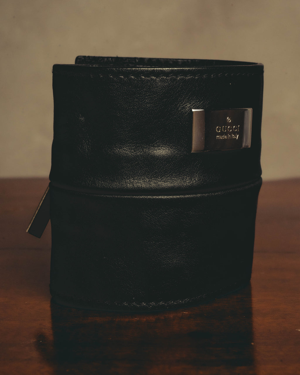 ブラックのシボ革によるワイドカフ正面を捉えたカット。GUCCI・made in Italyの刻印入り銀色メタルプレートと、左側に配されたジッパープルが確認できます。