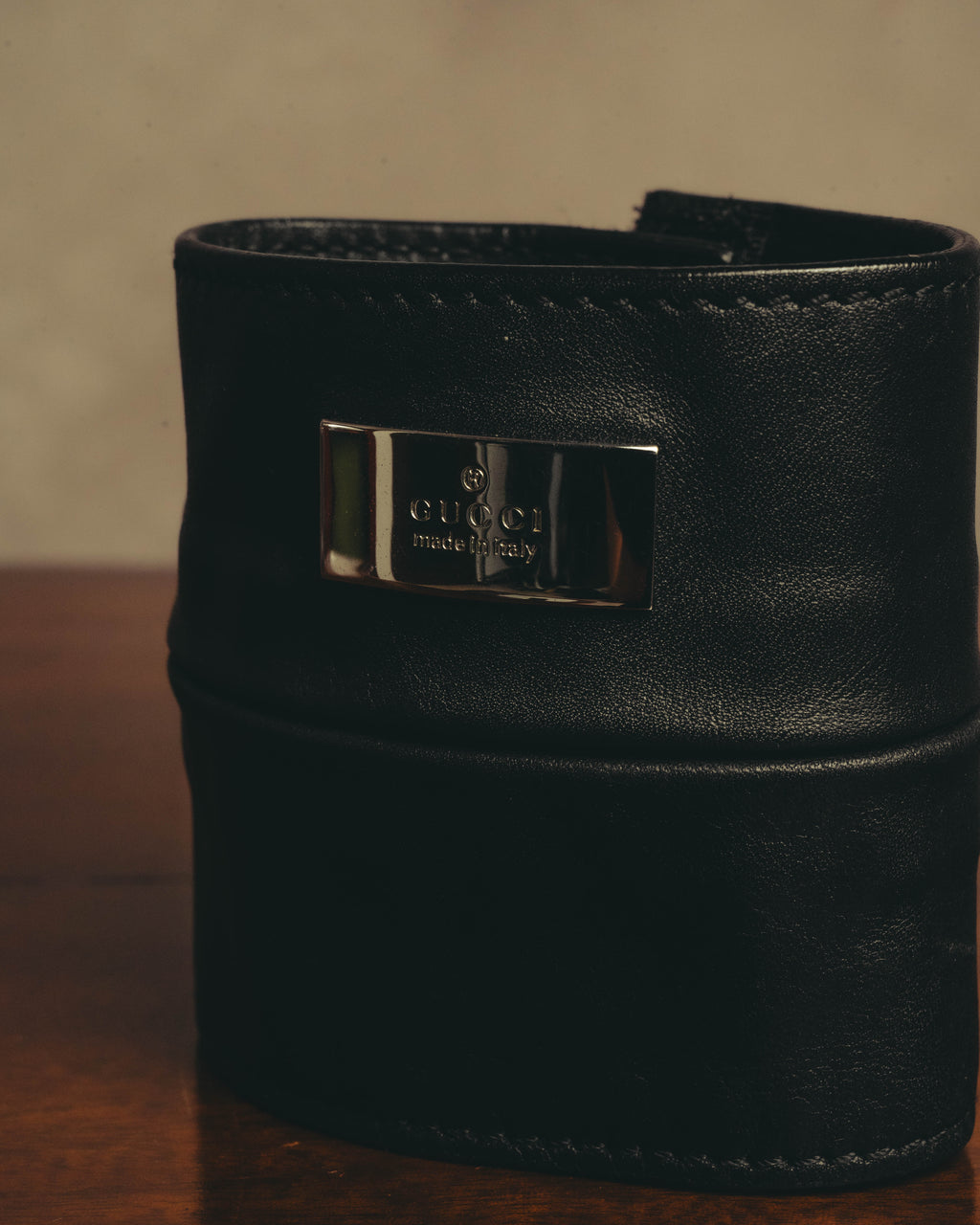 ブラックレザーのワイドカフ正面に配された、GUCCIとmade in Italyの刻印入り銀色メタルプレートのディテールカット。きめ細かなシボを備えた本体とのコントラストが確認できます。