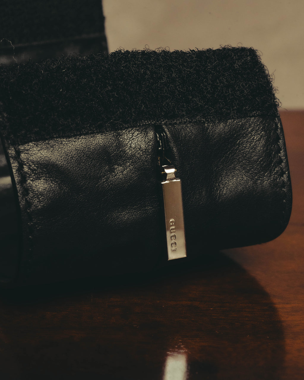 立体的なジップポケットに配された、GUCCI刻印入りの銀色ジッパープルを捉えたディテールカット。ブラックレザーのきめ細かなシボと、金具のコントラストが確認できます。