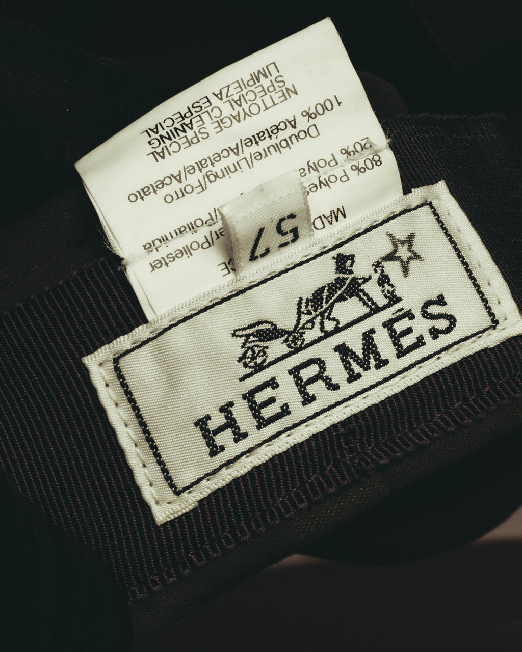 内側に配されたHERMÈSのブランドネームタグと、サイズ57表記を写したカット。品質表示タグにはポリエステル80％・ナイロン20％、裏地アセテート100％の素材表記が確認できます。