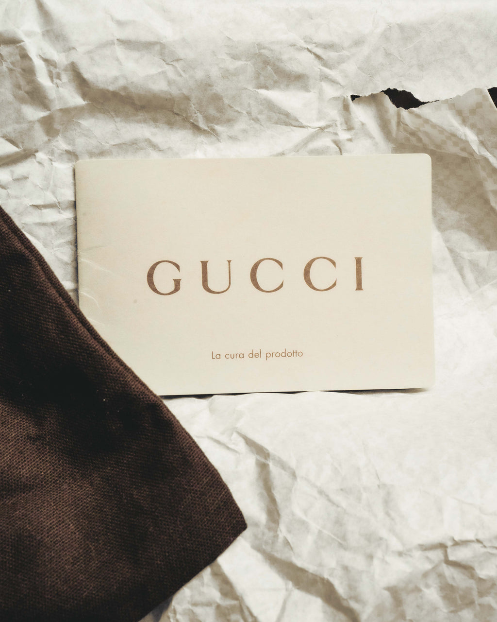 GUCCIロゴと「La cura del prodotto」の表記が確認できるケア冊子のカット。保存袋の一部とともに、付属品の仕様を示しています。