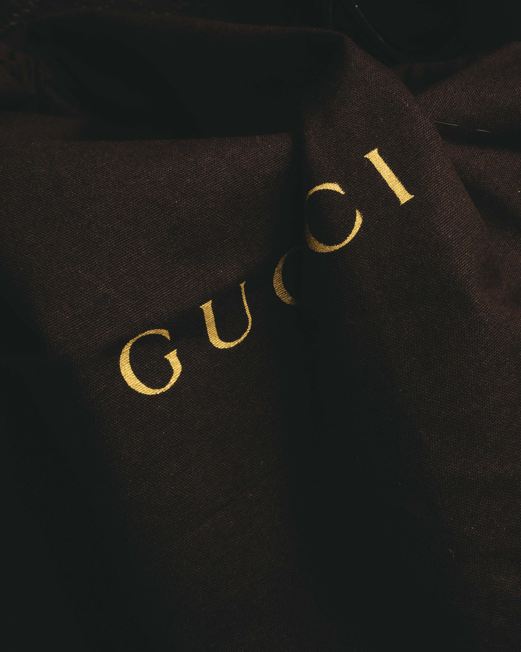 ブラックの保存袋に配されたゴールドのGUCCIロゴを捉えたディテールカット。付属品として確認できる保存袋の仕様に対応します。