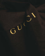 ブラックの保存袋に配されたゴールドのGUCCIロゴを捉えたディテールカット。付属品として確認できる保存袋の仕様に対応します。