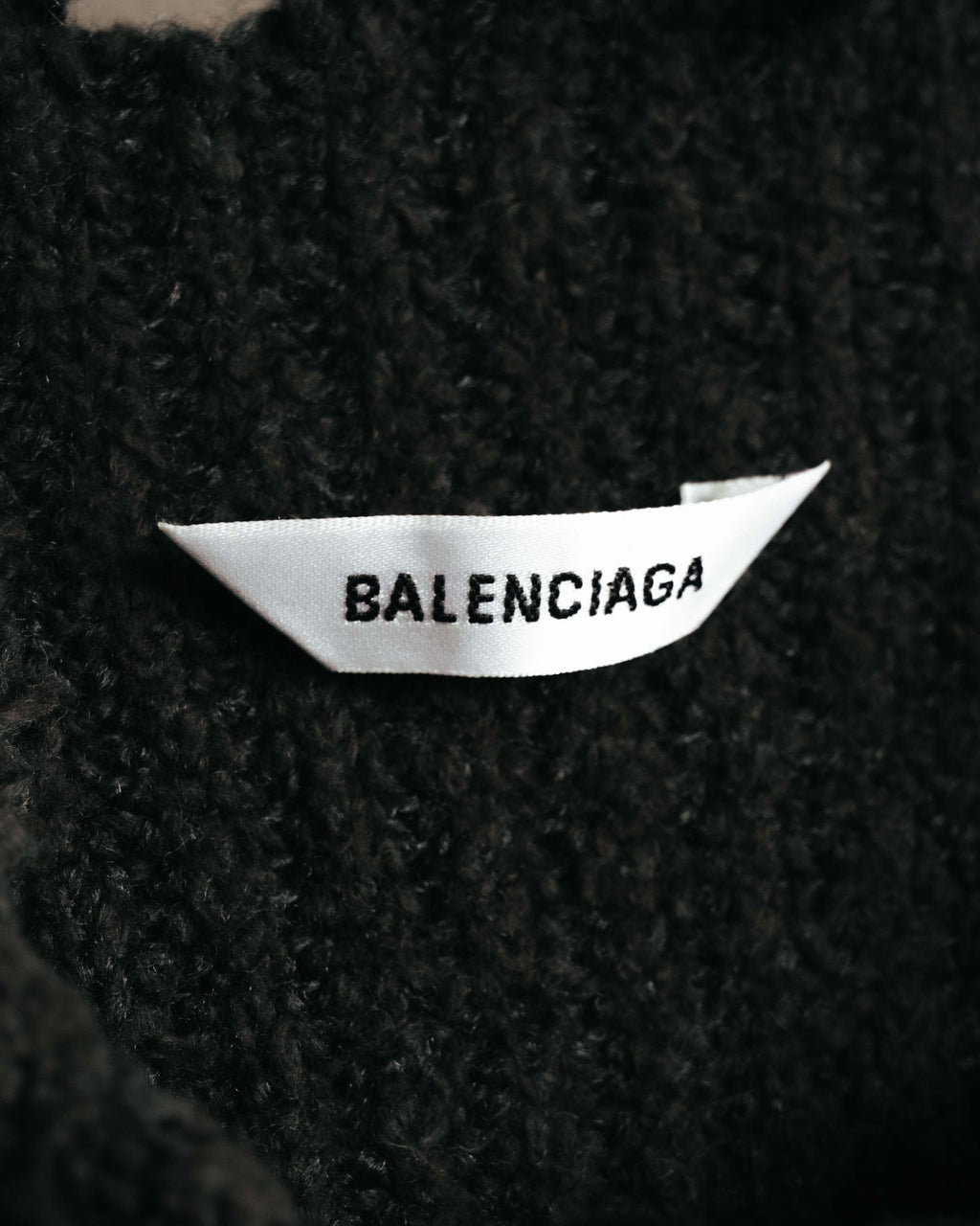 ブラックの起毛感ある編地に配された、BALENCIAGA表記のネックタグを確認できるカット。