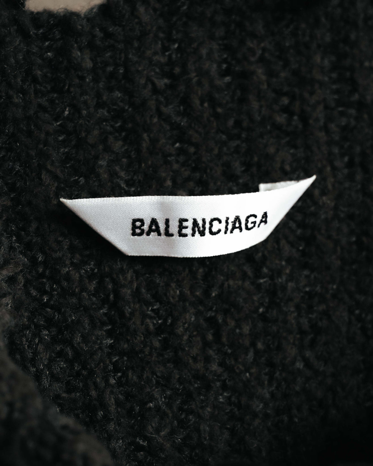 ブラックの起毛感ある編地に配された、BALENCIAGA表記のネックタグを確認できるカット。
