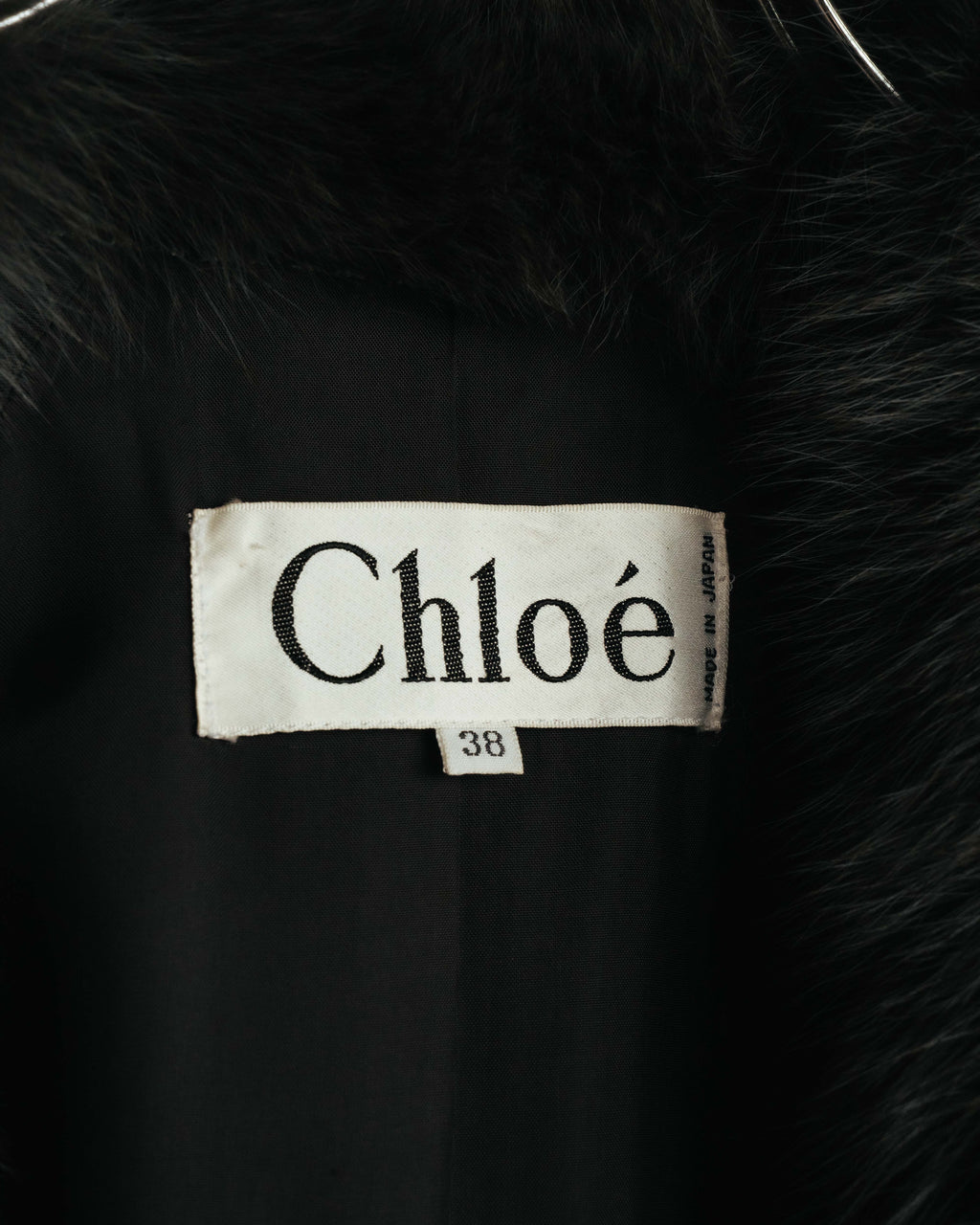 裏地側に配されたChloéのブランドネームタグと、サイズ38表記を確認できるカット。周囲にはファー状襟の毛足と滑らかなブラックの裏地が写されています。