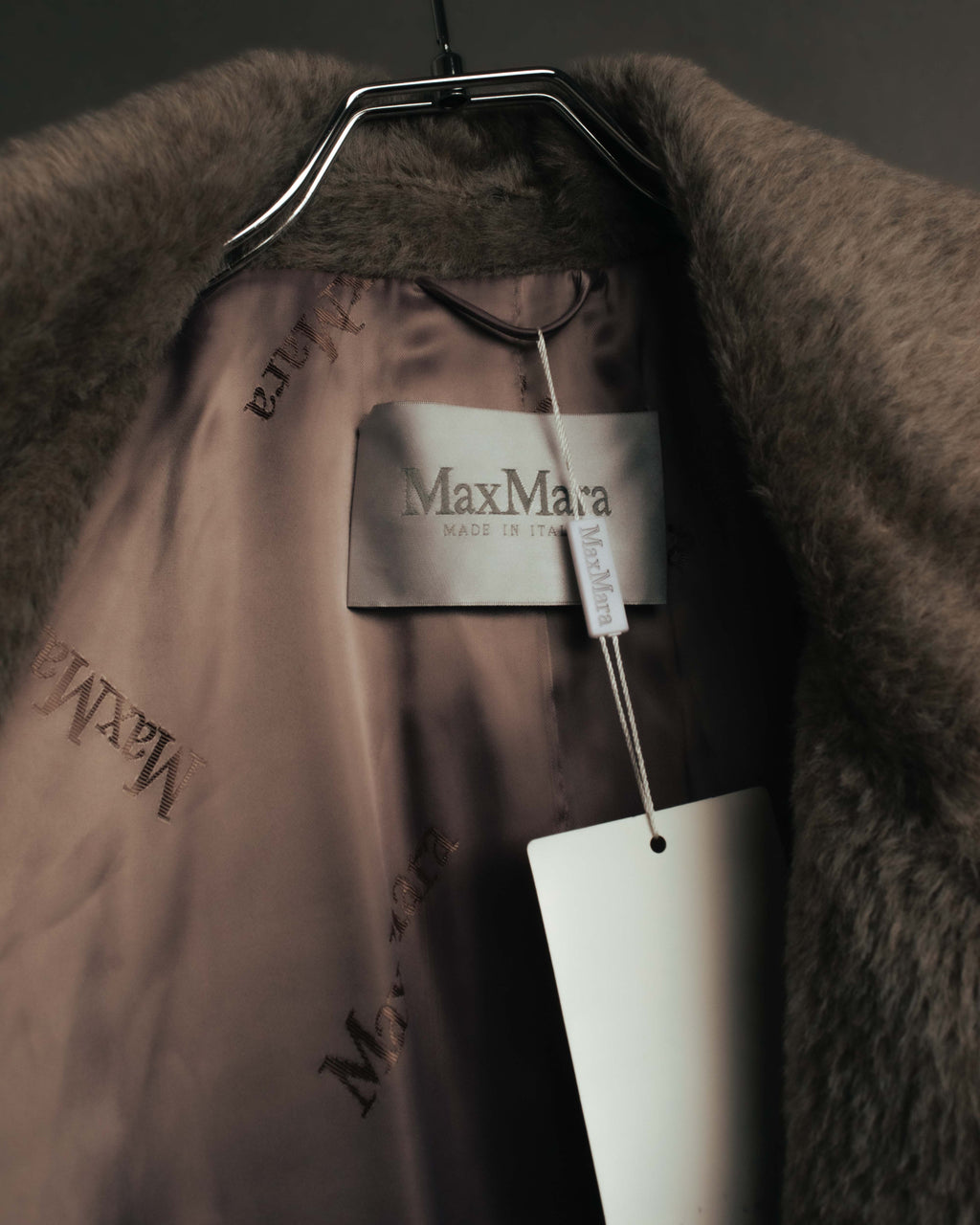 首元内側のMax Maraタグと、ブランドロゴが繰り返し配された光沢のある裏地を写したカット。毛足のある表地と裏地の質感の対比も確認できます。