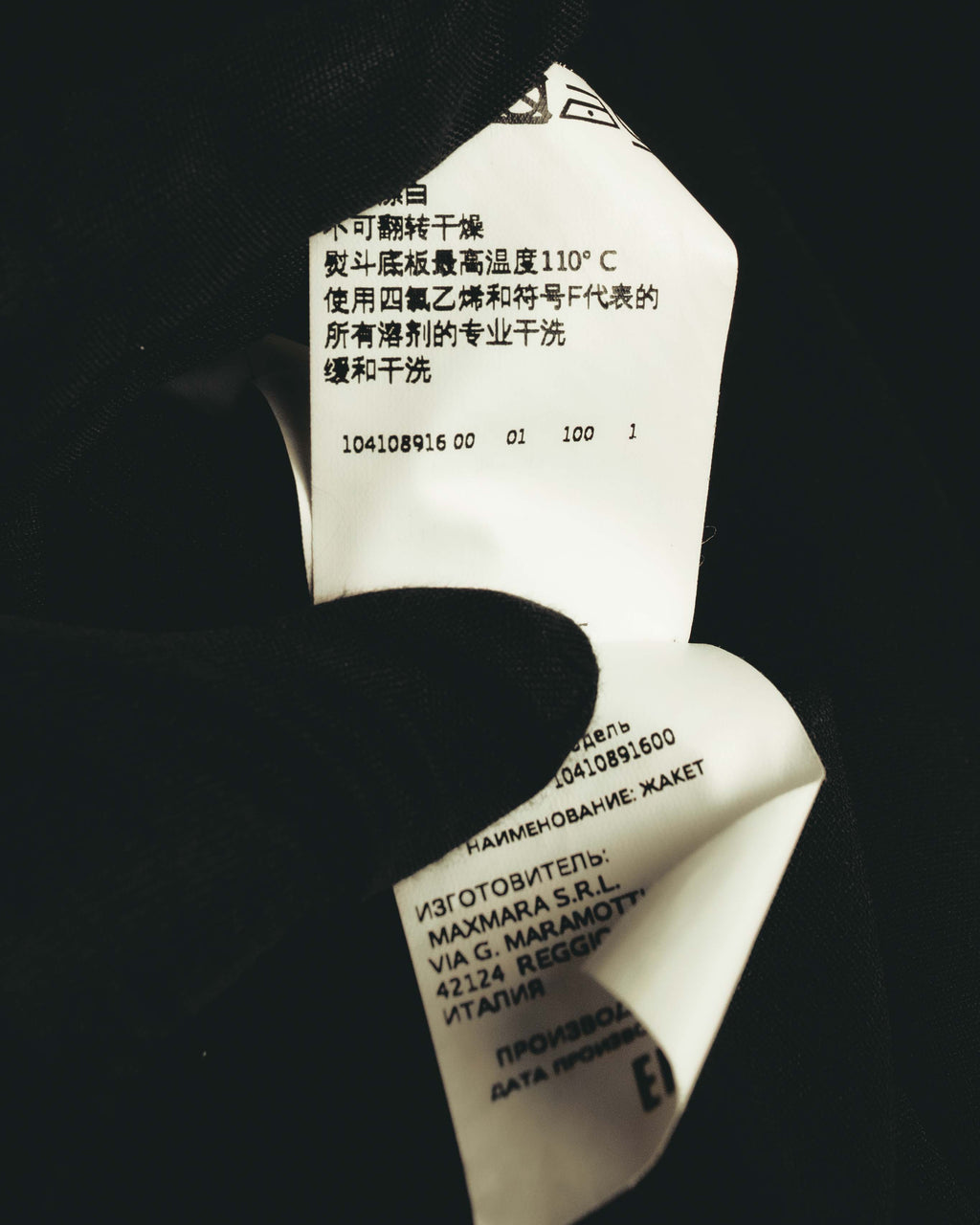 内側に配された多国表記の品質表示タグを写したカット。製造元表記とケア表示、品番が確認できる仕様です。