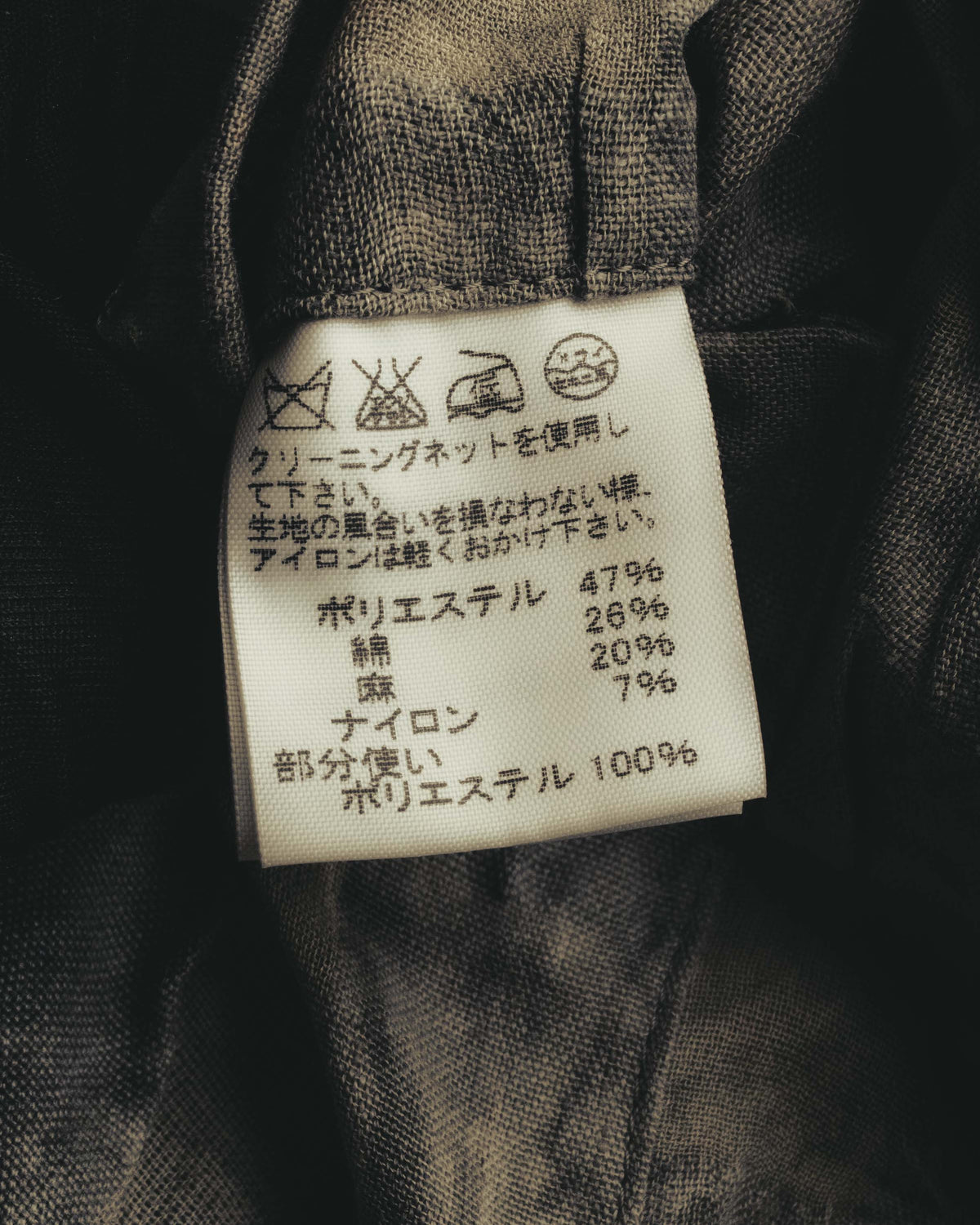 旧JIS方式の洗濯記号を配した品質表示タグのカット。ポリエステル47%、綿26%、麻20%、ナイロン7%の混紡表記を確認できます。