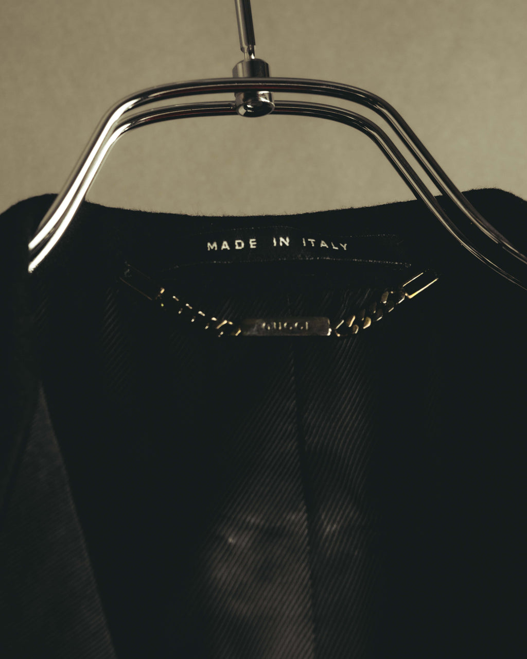 内側の襟元に配された「MADE IN ITALY」表記と、チェーン式ハンガーループの刻印を捉えたディテールカット。総裏地の織り模様も確認できます。