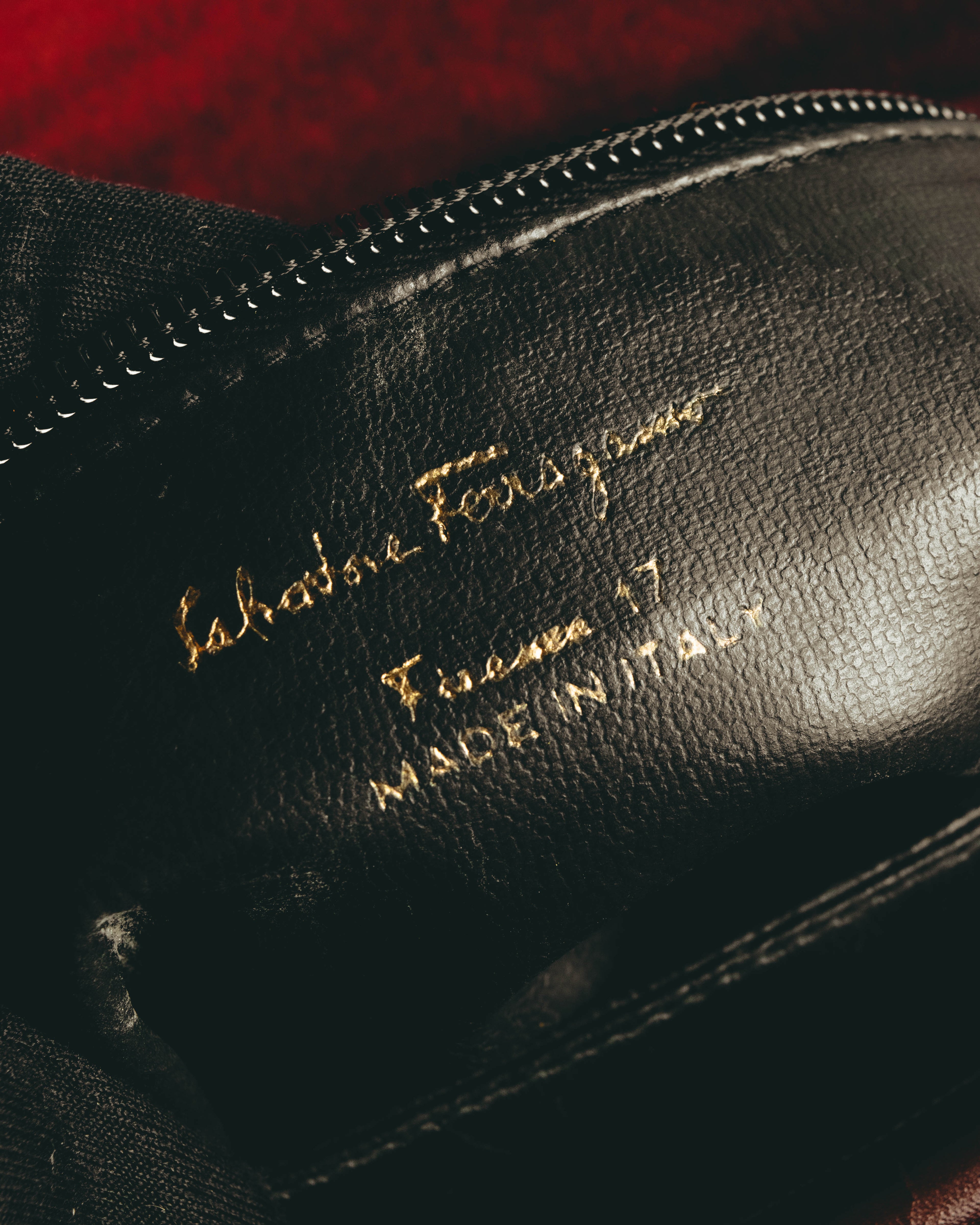 ブラックの内装へ直接施された、Salvatore Ferragamo、Firenze 17、MADE IN ITALYの金色箔押しを捉えたカット。内装のレザー質感と縁のステッチも確認できます。