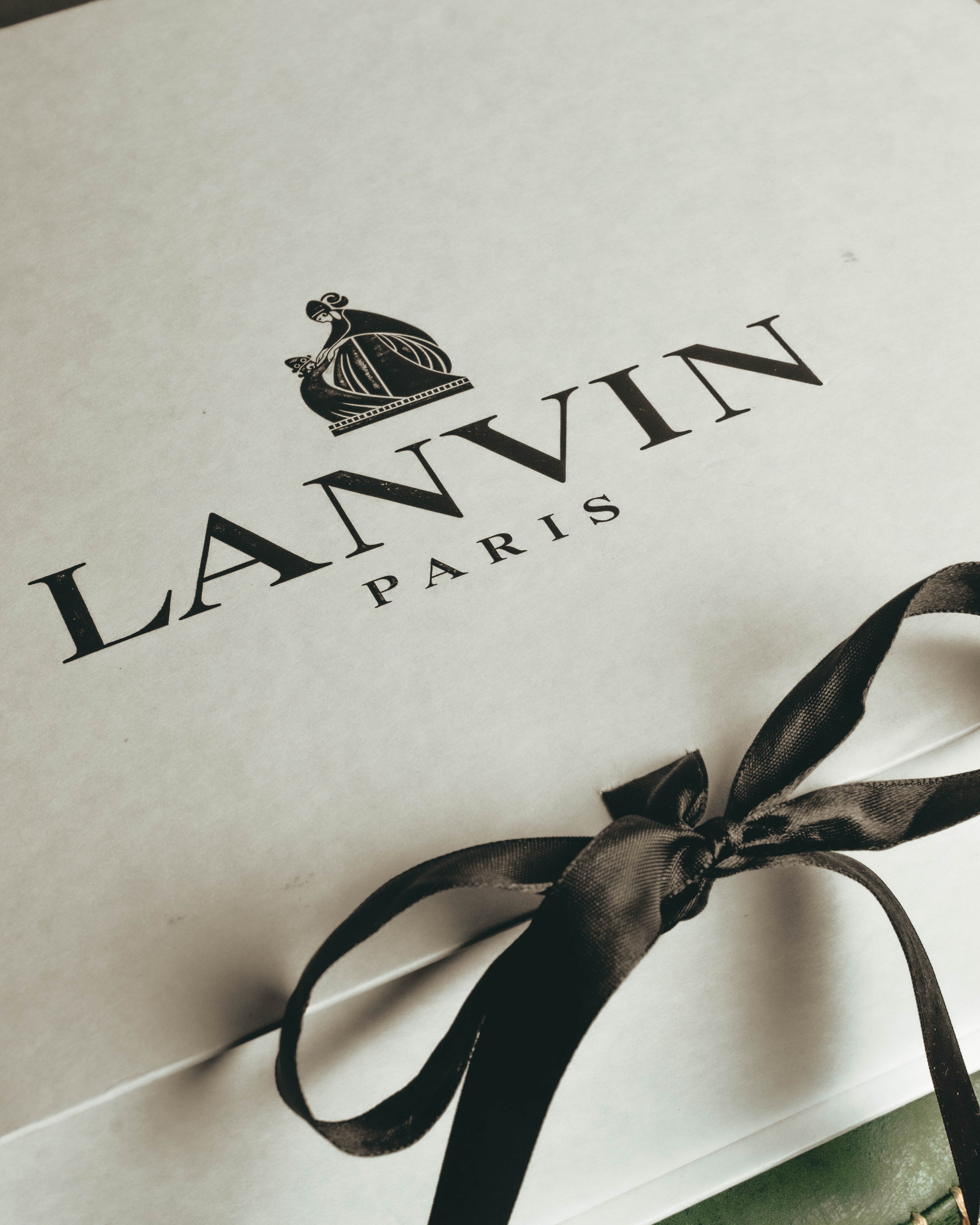 母子像のロゴとブランド名が印刷されたボックスに、黒いリボンを掛けた付属品のカット。付属する箱に確認できる母子像の意匠を捉えています。