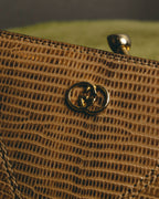 細かな横列状の鱗模様を持つリザード外装に、フロントのインターロッキングGG形金具と口金式フレームを配したディテールカット。