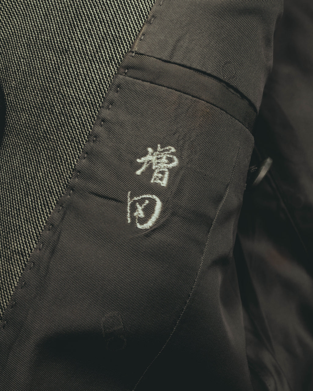 ジャケット内側に配された「毛」の品質表示刺繍と、細やかな織りを捉えたディテールカット。滑りの良いキュプラ裏地との切り替えも確認できます。
