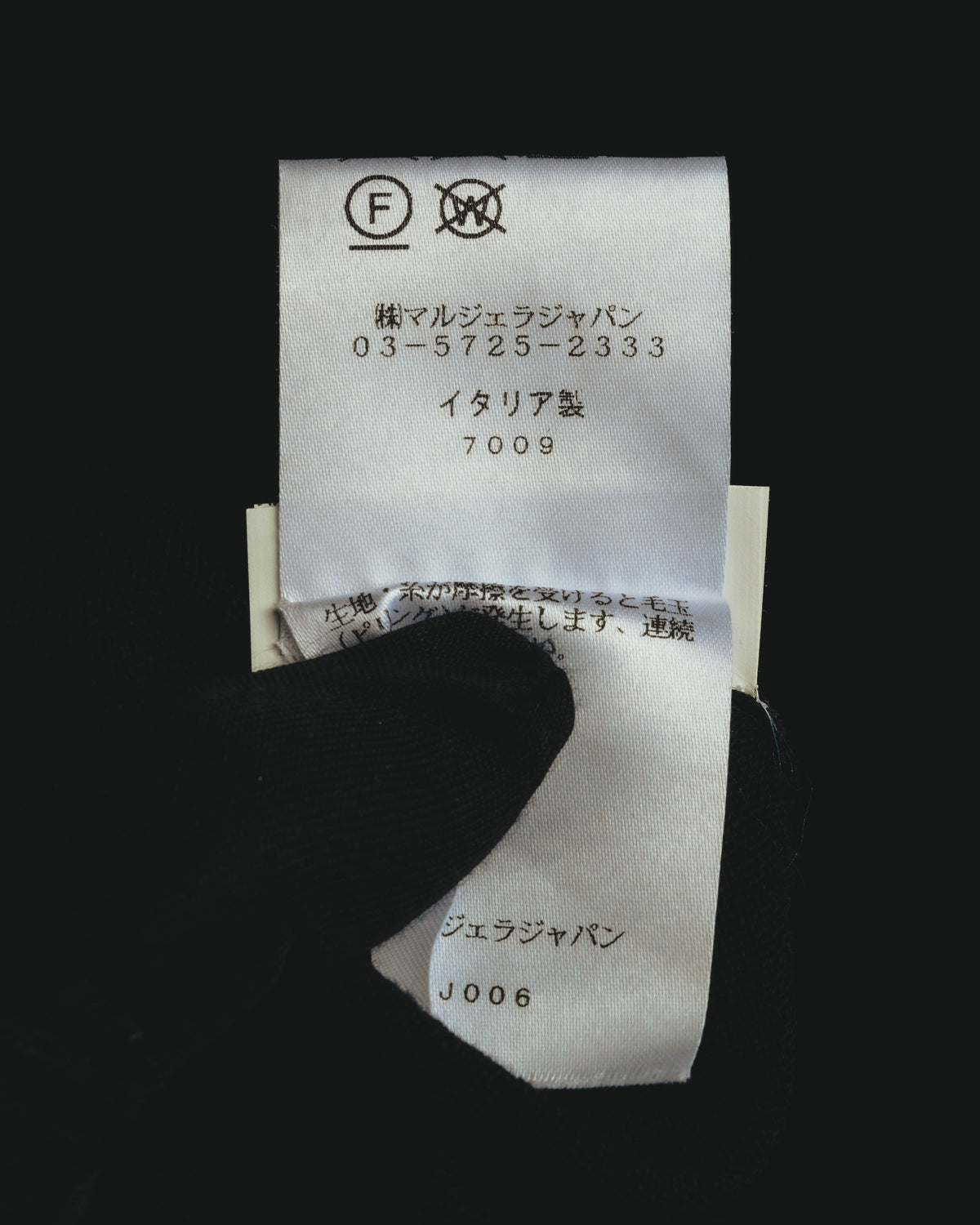 内側の洗濯表示タグに、株式会社マルジェラジャパンの表記とイタリア製の表記を確認できるカット。新JIS系の洗濯表示が写されています。